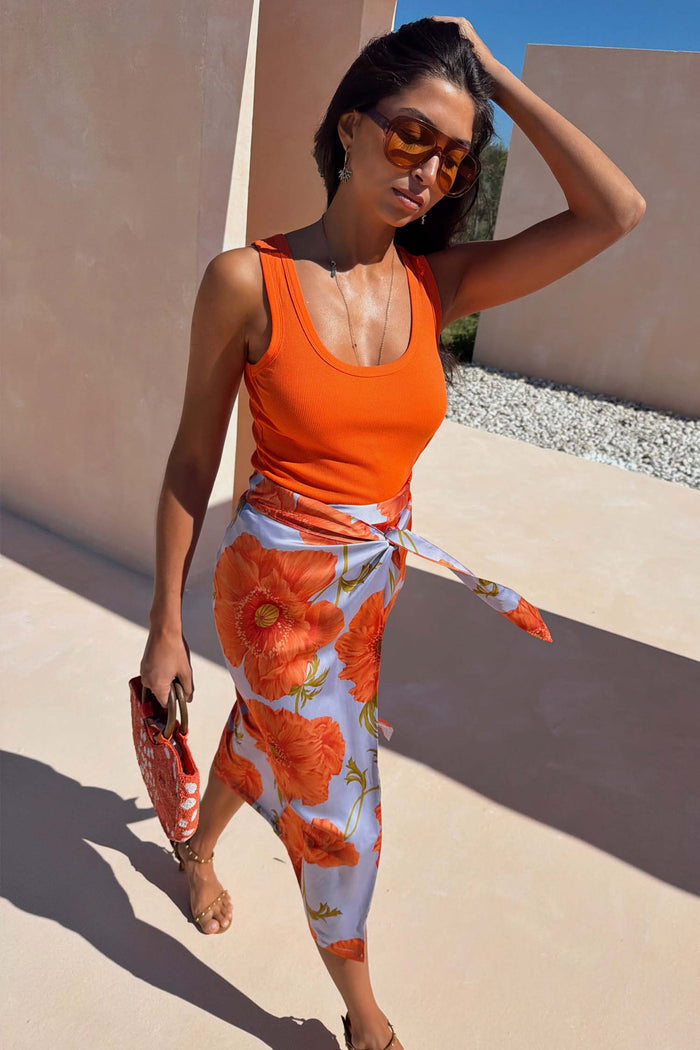 Iconic Blue Poppy Jaspre Skirt with orange floral print and wrap tie fastening, styled for a sunny vacation look.