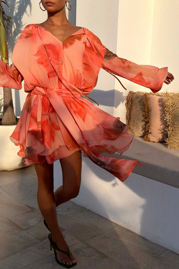 Blurred Floral Ella Mini Dress in peach orange with flute sleeves and tiered ruffles, styled for a vacation.