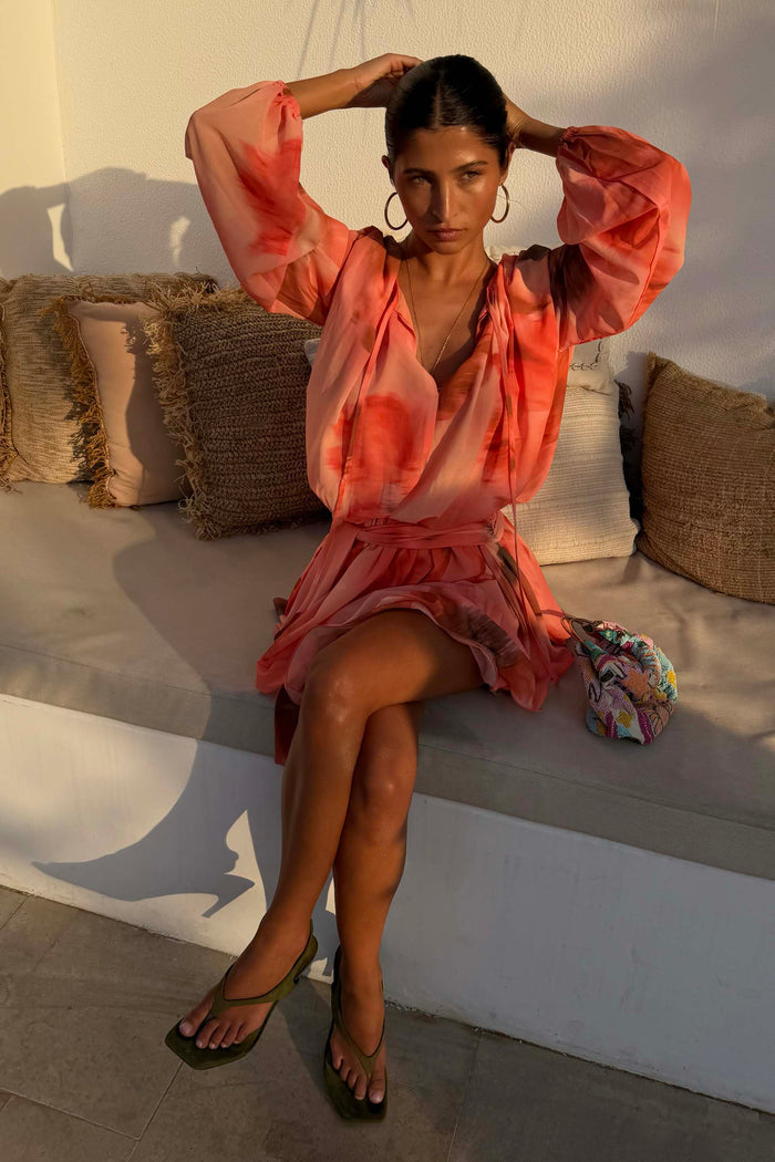 Peach orange Blurred Floral Ella Mini Dress featuring flute sleeves and a tiered ruffle skirt, styled outdoors.