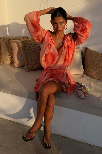 Peach orange Blurred Floral Ella Mini Dress featuring flute sleeves and a tiered ruffle skirt, styled outdoors.