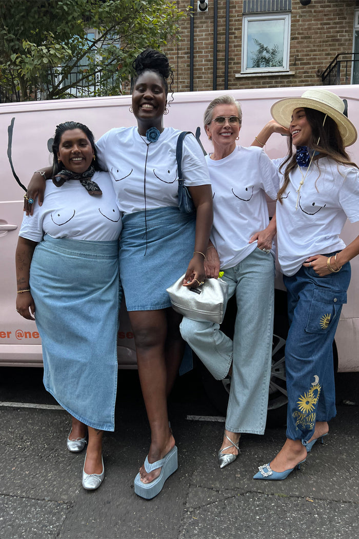 Iconic white Boob T-shirts with black line graphics styled with denim on diverse women by a pink van.