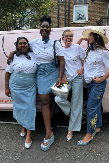 Iconic white Boob T-shirts with black line graphics styled with denim on diverse women by a pink van.