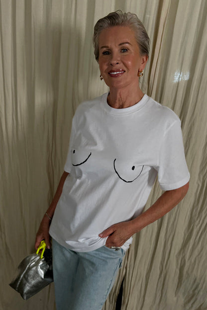 Iconic white Boob T-shirt with a black line graphic, paired with blue jeans and a silver bag.