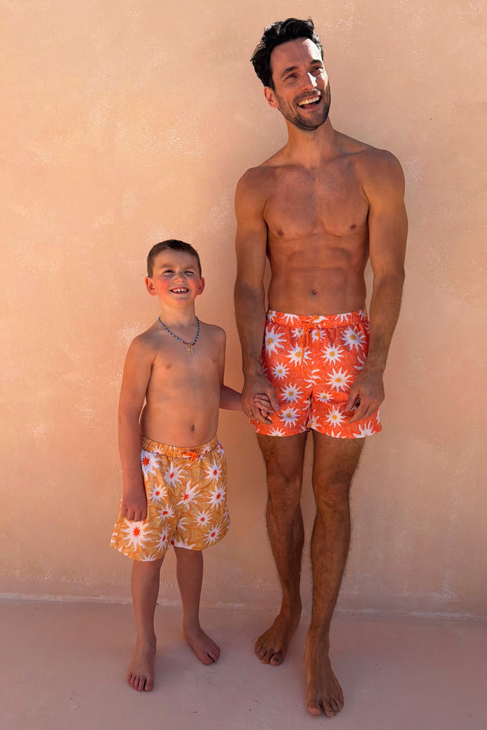 Boy's Yellow Sun Swim Shorts with a white sun print, worn by a boy and man for a matching family vacation look.