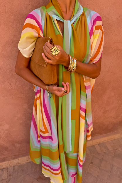 Bright Geo Stevie Maxi Dress featuring colourful geometric stripes and a scarf-tie neck, styled with a tan suede clutch.