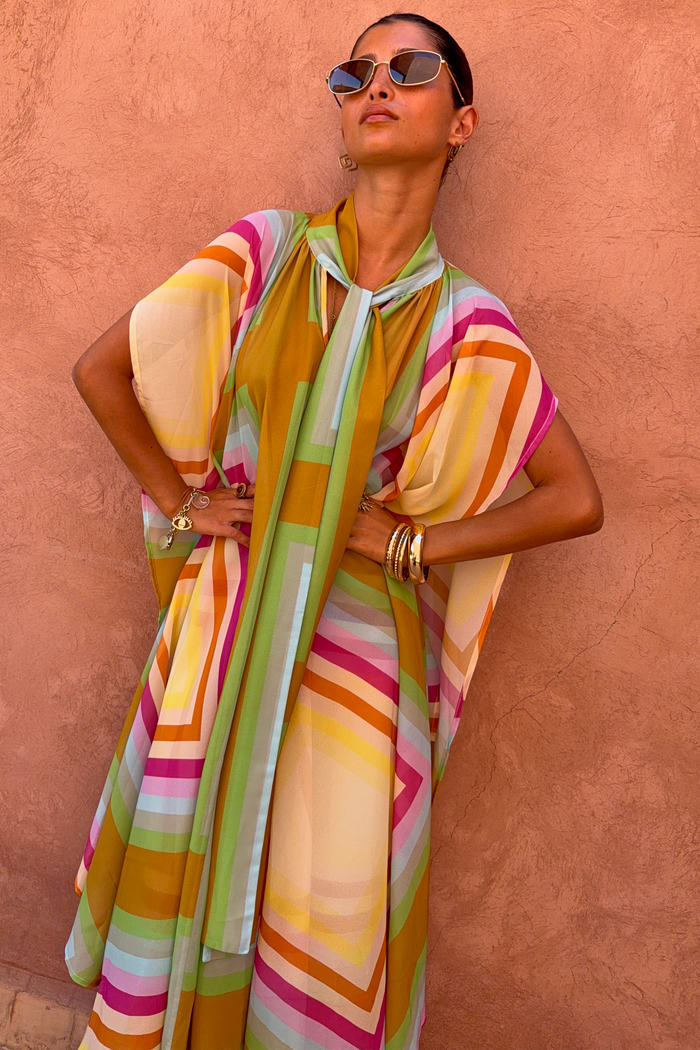 Bright Geo Stevie Maxi Dress with a colourful geometric stripe print and scarf-tie neckline on a model.
