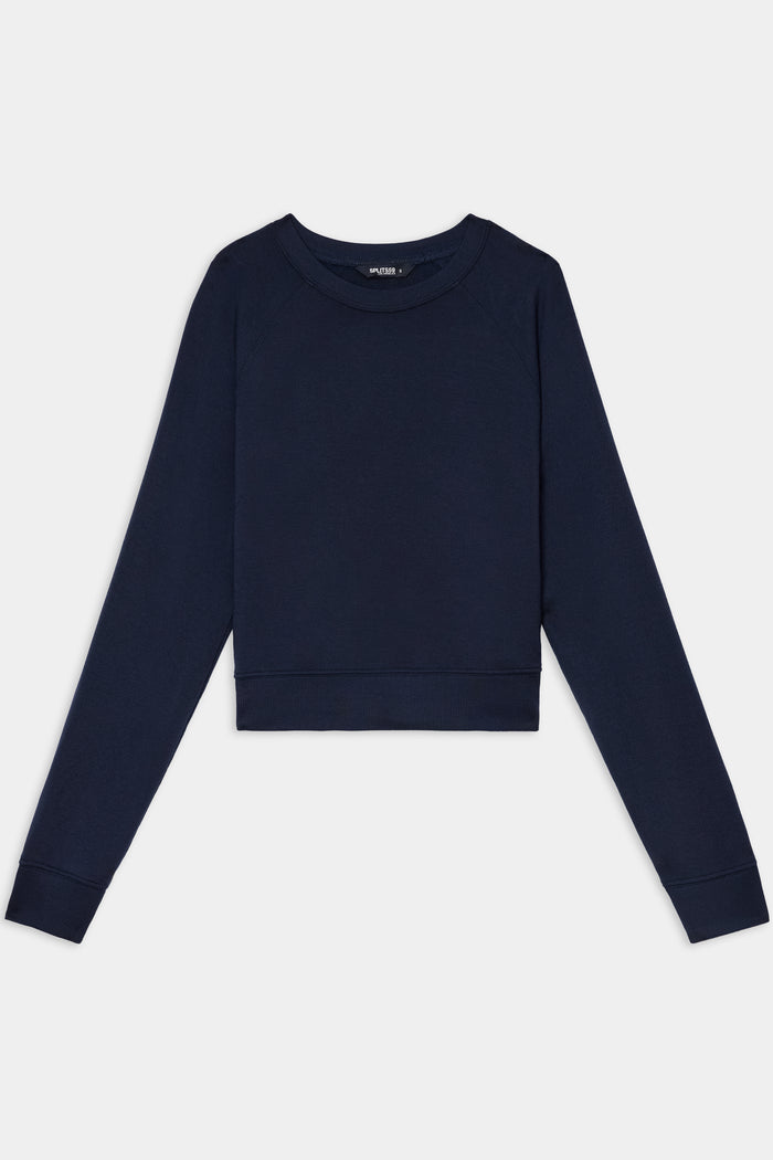 The SPLITS59 Brooks Fleece Long Sleeve Sweatshirt in Indigo features a cropped silhouette with long raglan sleeves and a crewneck, shown laid flat on a white background.
