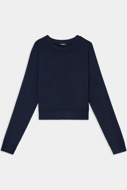The SPLITS59 Brooks Fleece Long Sleeve Sweatshirt in Indigo features a cropped silhouette with long raglan sleeves and a crewneck, shown laid flat on a white background.