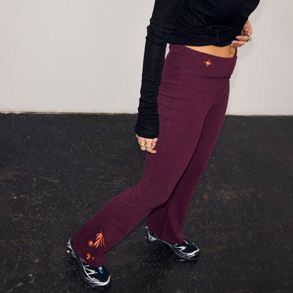 Burgundy cotton flared trousers featuring coral embroidery at the waist and hem.