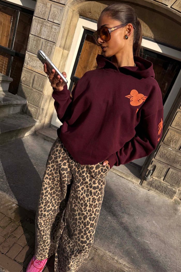 Burgundy cotton-blend hoodie with coral orange embroidery and leopard print trousers for a London look.