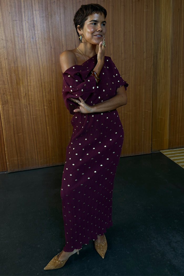 Multi-wear Burgundy Tilly Dress in gold-flecked plisse fabric, styled off-the-shoulder on a model.