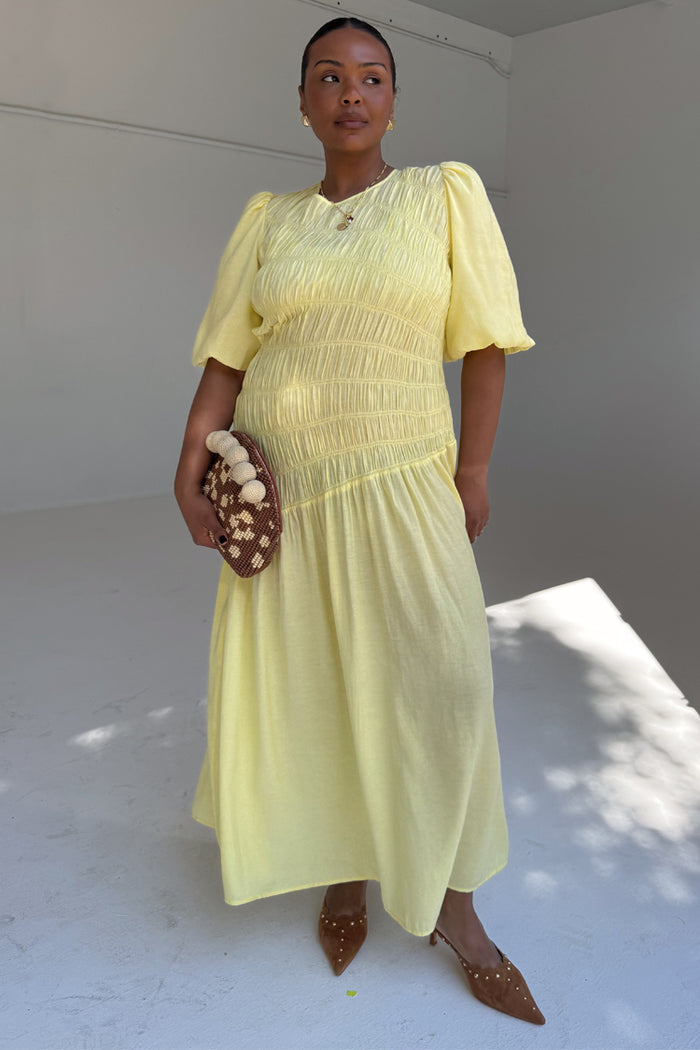 Butter yellow Nara dress with a shirred bodice and puff sleeves, styled on a curve model for inclusive sizing.