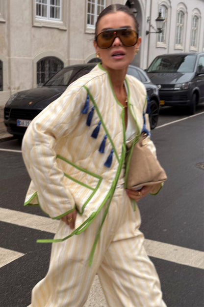Butter Yellow Stripe Quilted Jacket featuring green trim and blue tassels, styled as a street style co-ord.