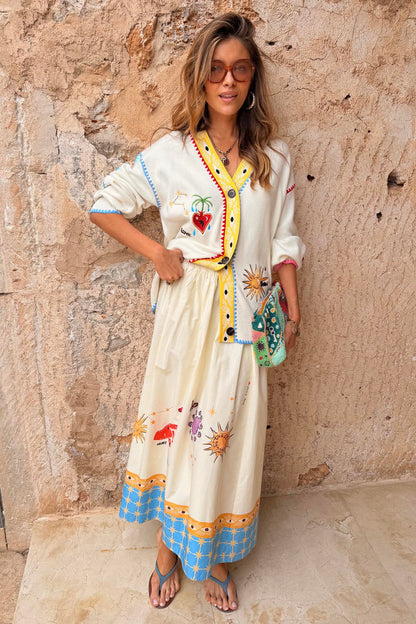 Celestial Talia Skirt in breathable cotton with a sun and palm print and blue border, paired with a matching cardigan.