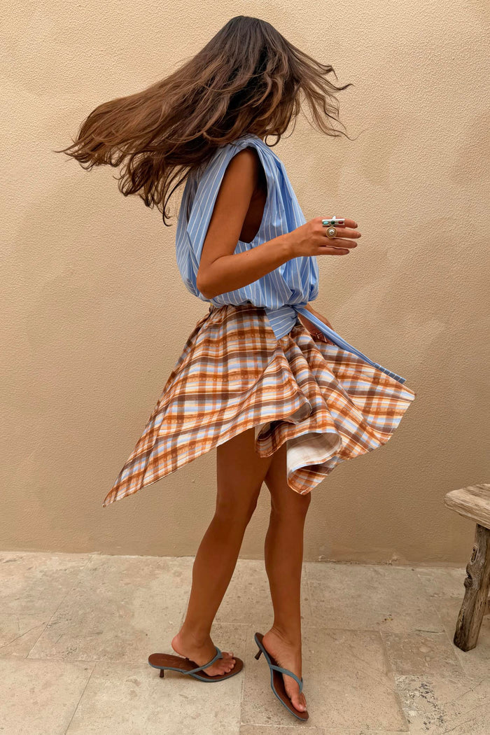 Check Asymmetric Mini Skirt featuring a blue and brown check print, hanky hem and striped tie-waist detail.