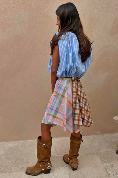 Check Asymmetric Mini Skirt featuring a mixed check print, hanky hem, and stripe detail, styled with brown boots.