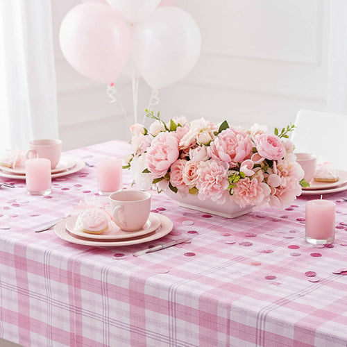 Decorative table setting with pink flowers, checkered tablecloth, and balloons.