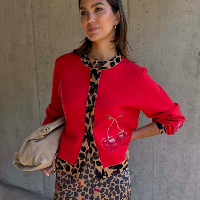 Cherry Holly Cardigan in red with leopard print trims and cherry motifs, styled with a leopard skirt.