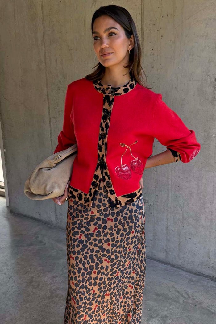 Red Cherry Holly Cardigan featuring leopard trim and cherry motifs, styled over a leopard print dress.