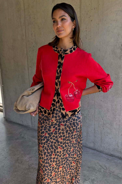 Red Cherry Holly Cardigan featuring leopard trim and cherry motifs, styled over a leopard print dress.