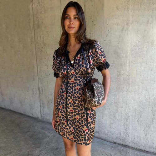 Cherry Leopard Mini Lyla Dress with black lace trims, tie neck and puff sleeves, styled with a coordinating clutch bag.