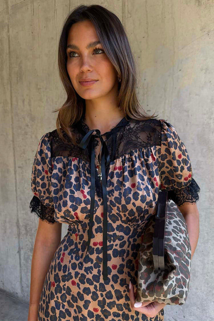 Cherry Leopard Mini Lyla Dress with black lace trims, ribbon tie neck, and a leopard print featuring tiny red cherries.