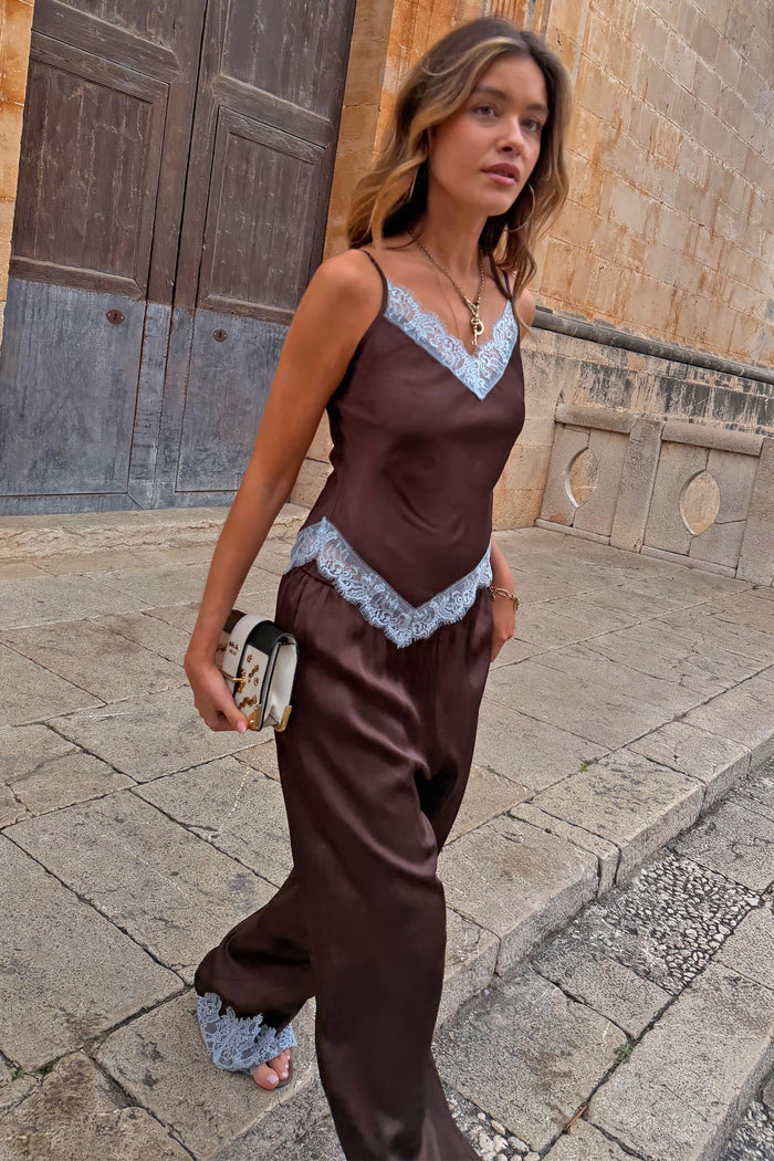 Chocolate Aurelia satin-esque top with blue lace trim, styled with matching trousers on a model walking outdoors.