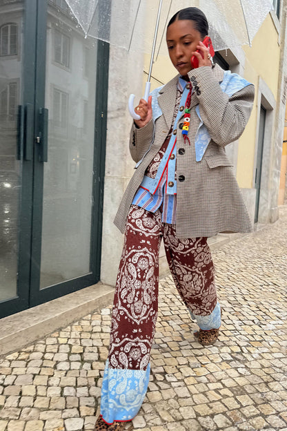 Chocolate Bandana Wide Leg knit trousers with a blue hem, paired with a check blazer on a cobblestone street.
