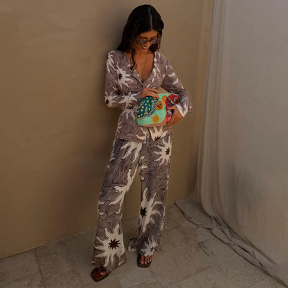 Chocolate Soleil Ellie Trousers and matching cardigan with sun motifs, styled with a colourful beaded clutch bag.