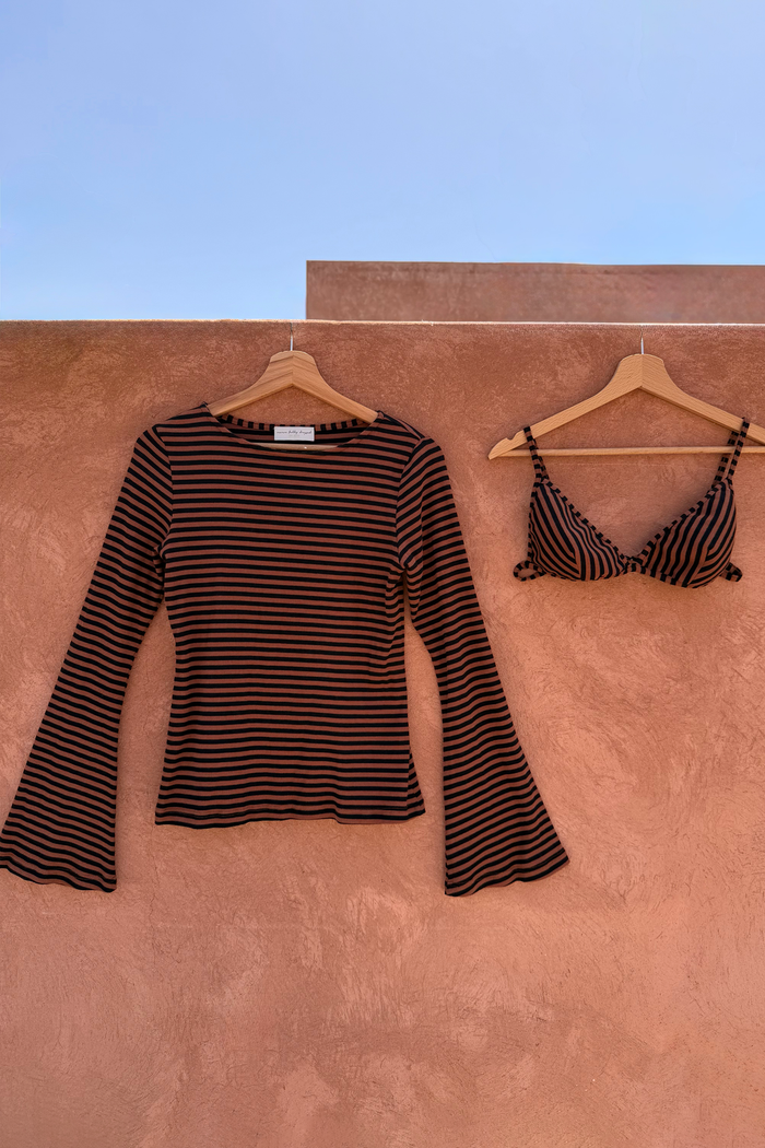 Ribbed chocolate stripe top with flared sleeves and matching bra set hanging against a terracotta wall.