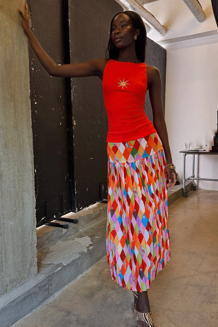 Pleated Cirque Beatrice Skirt with a colourful geometric diamond pattern and circus motifs on a model.