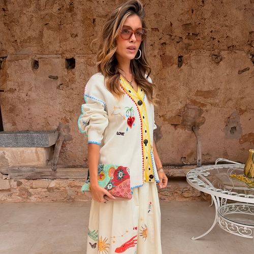 Cream Celestial Martha Cardigan in a soft-touch knit with embroidered motifs and a yellow hem, styled with a matching skirt.