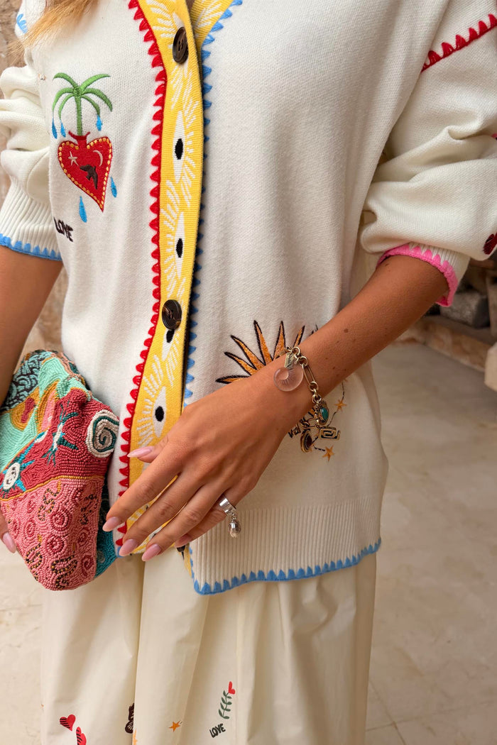 Soft-touch Cream Celestial Martha Cardigan featuring sun and heart motifs with a vibrant yellow button placket.