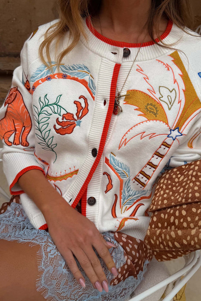 Cream Cheryl Cardigan featuring Tigress Print embroidery, palm trees, and vibrant orange contrast trims.