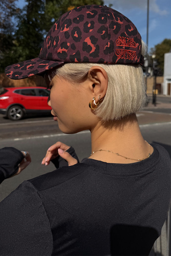 Dark Leopard Cap in iconic leopard print with burgundy tones and embroidered logo, styled on a model in a London street.