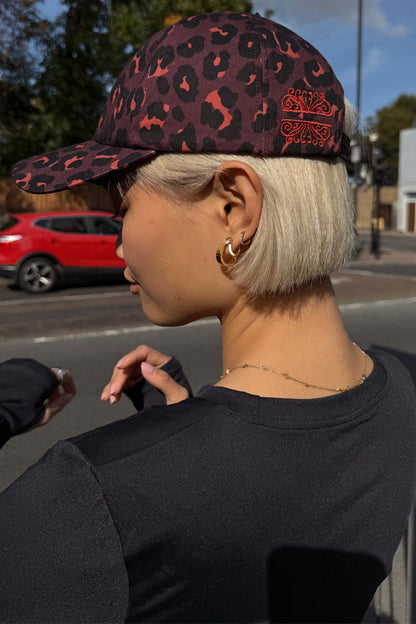Dark Leopard Cap in iconic leopard print with burgundy tones and embroidered logo, styled on a model in a London street.