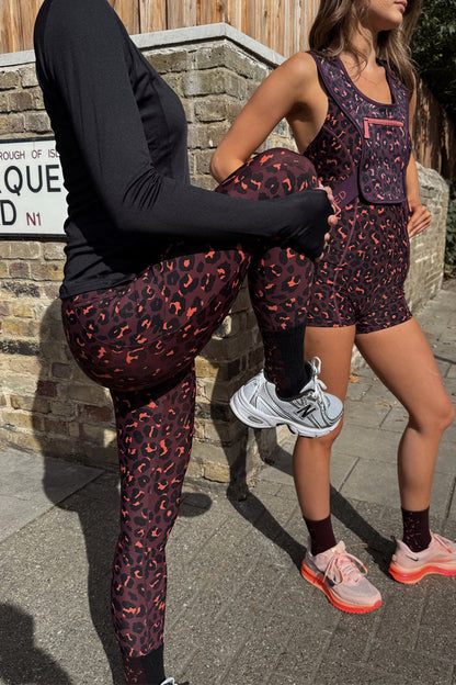 Dark Leopard Leggings in a burgundy animal print with orange accents, styled for activewear on a London street.