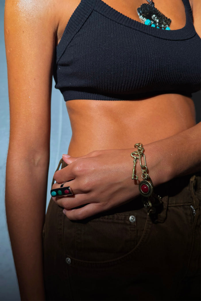 Deloris Charm Bracelet in brushed gold featuring a key motif and chunky chain links, worn on a wrist.