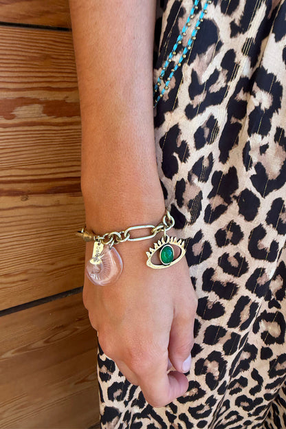 Deloris Charm Bracelet in brushed gold with eye and mermaid charms, worn with a leopard print dress.
