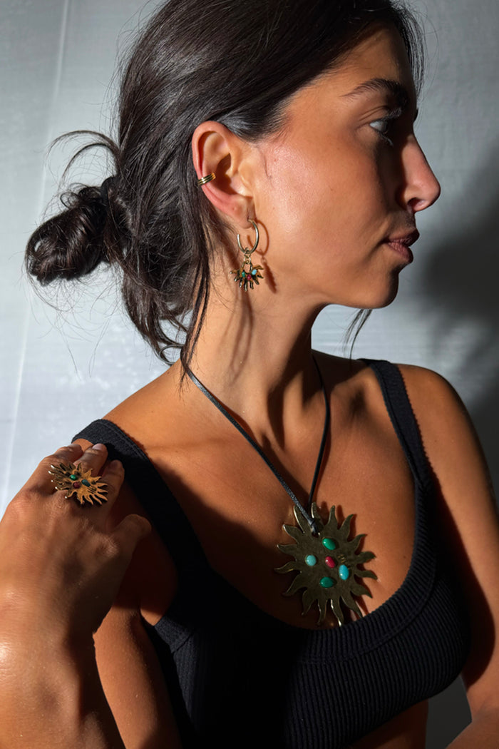 Deloris Sun Hoop Earrings in brass with iconic sun motifs and semi-precious stones, worn by a model in profile.