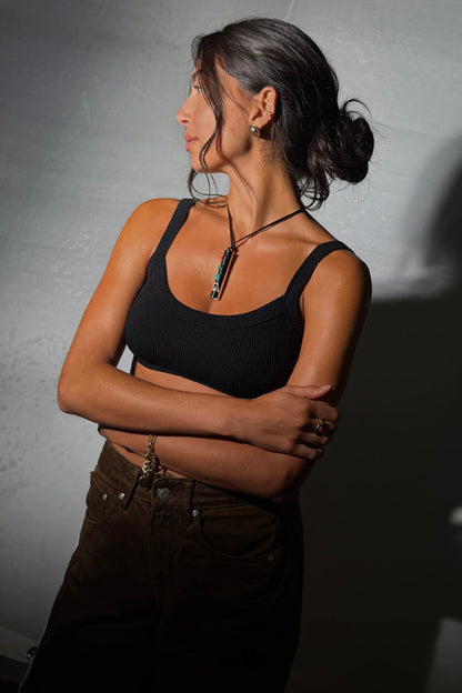 Deloris Whistle Necklace featuring a brass pendant and colourful stones on a black leather cord, styled on a model.