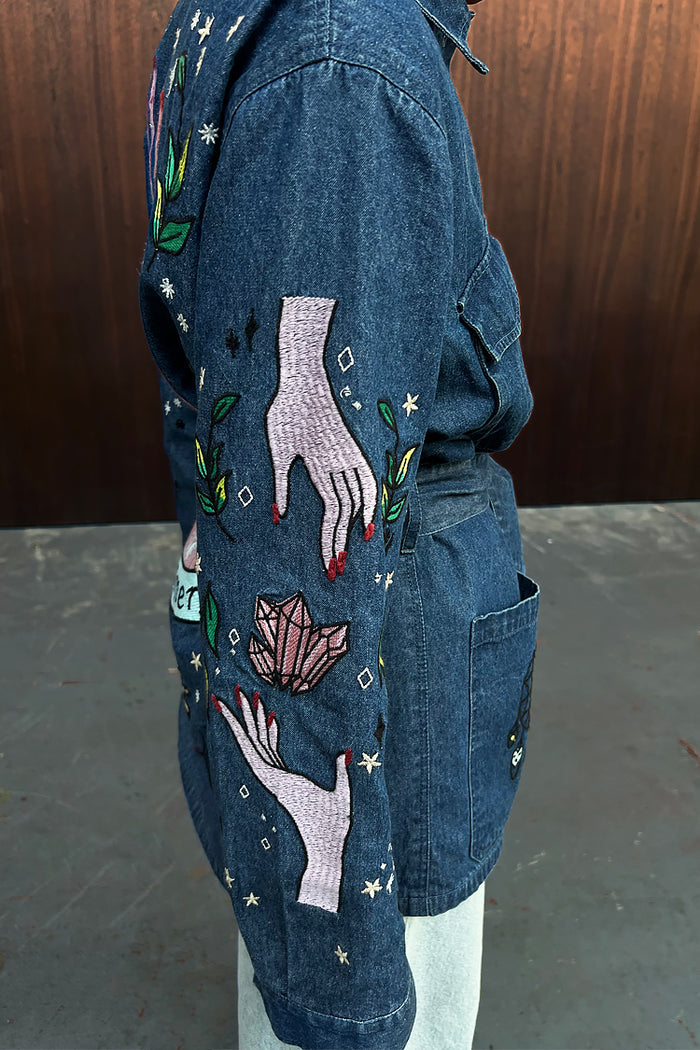Blue Denim Manifestation Jacket featuring Tarot-inspired hand and crystal embroidery on the sleeve.