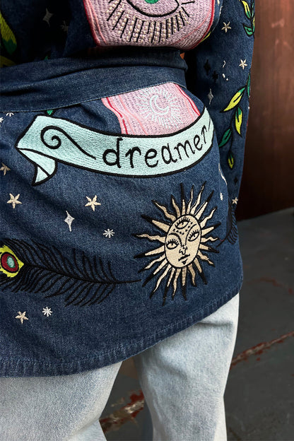 Blue denim jacket featuring embroidered tarot-inspired motifs, a dreamer banner, and sun detail on the back.