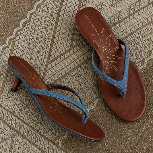 Denim Sandal Mules featuring slim blue straps, a low sculpted kitten heel, and brown cushioned soles with a sun motif.