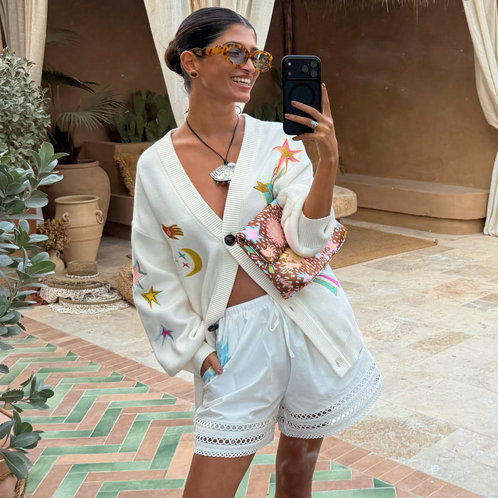 White cotton Dreamer Ellie Shorts with a cut-out hem and sun and eye motifs, styled with a celestial cardigan.