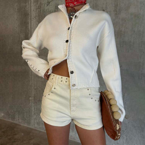 Ecru Studded Hot Pant with silver stud detailing, styled with a matching cream knit cardigan and a textured brown clutch.