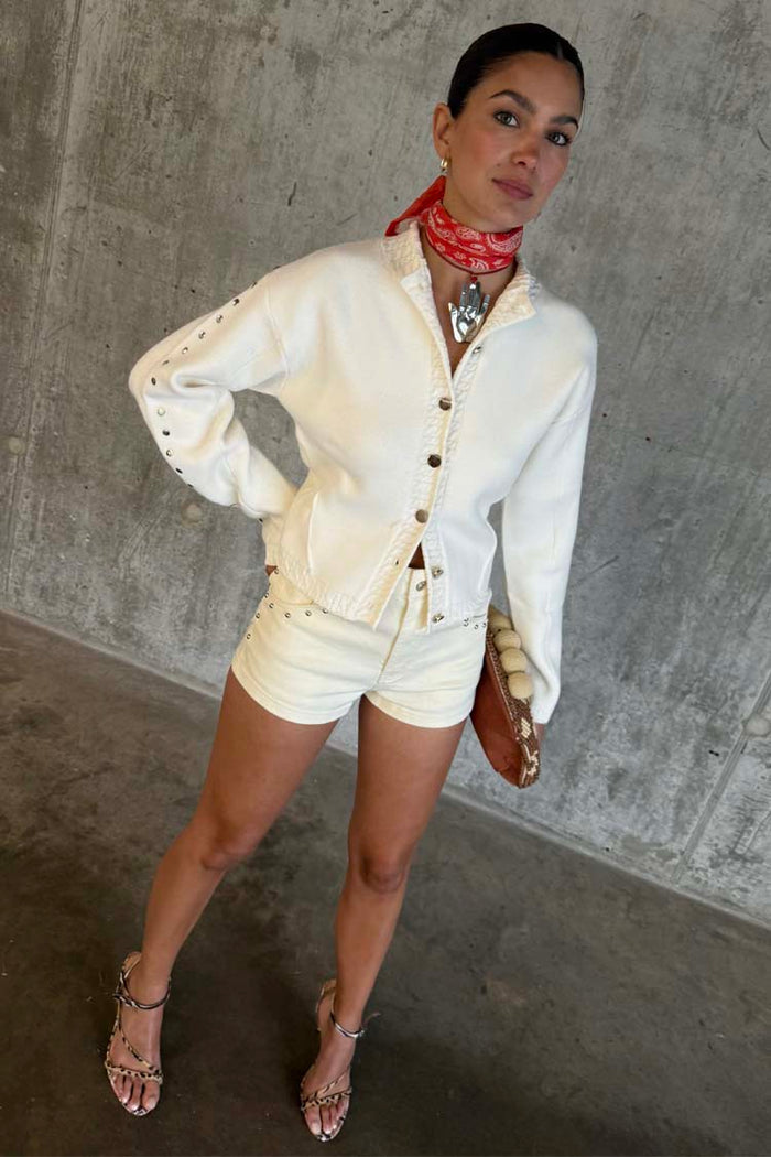 Ecru Studded Hot Pant with silver studs, styled with a matching jacket and red bandana neckerchief.