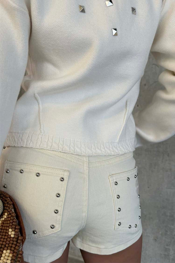 Ecru Studded Hot Pant with silver details on back pockets, paired with a matching cream top.