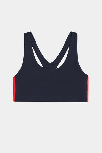 The SPLITS59 Ella Airweight Bra in Indigo/Pirate Red features a racerback design with red side panels, perfect for hot yoga, and is displayed on a plain white background.
