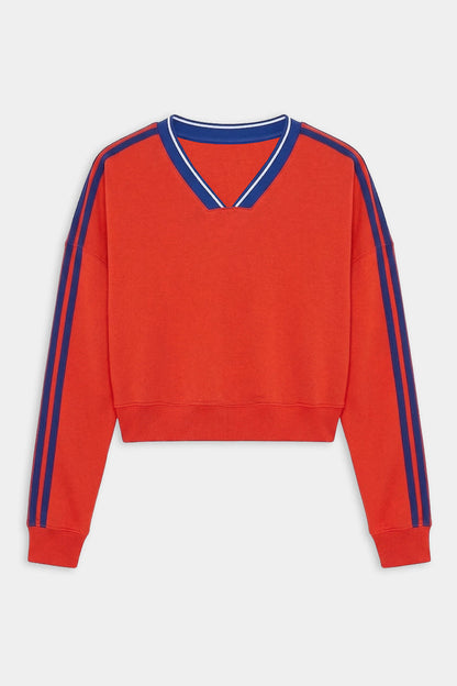 The SPLITS59 Ellie Fleece V Neck Sweatshirt in Lotus Red/Cobalt features blue double stripes on the shoulders and sleeves, a blue-trimmed V-neck, and is made from a soft spandex blend for comfort and stretch.